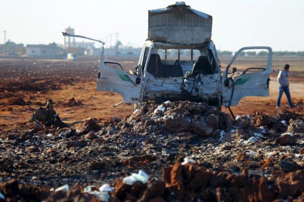 A man walks near a damaged truck at a site hit by what activists said were airstrikes carried out by the Russian air force in Karf Naseh town, Aleppo countryside, Syria December 26, 2015.