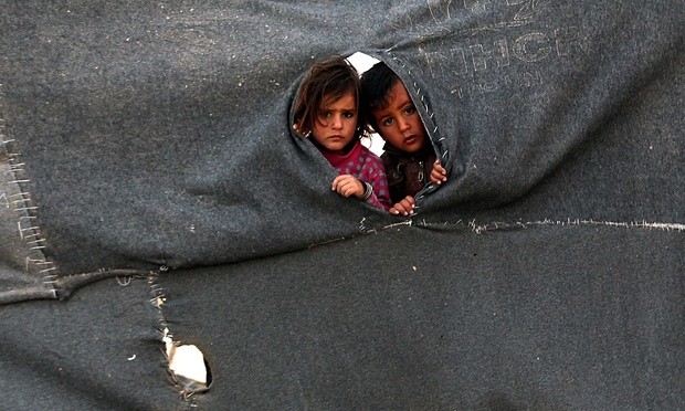 Two Syrian child refugees peer through a makeshift barrier at the Zaatari camp in Jordan. Photograph: Mohammad Abu Ghosh/Xinhua Press/Corbis