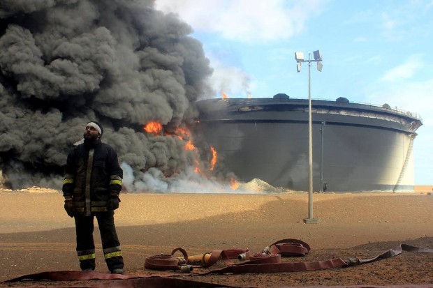 A firefighter stands in front of an oil storage tank in northern Libya's Ras Lanouf region on Jan. 23 after attacks launched by Islamic State. Libya is emerging as a new destination of choice for extremists, a report released by a security consulting firm said Wednesday. PHOTO: AGENCE FRANCE-PRESSE/GETTY IMAGES