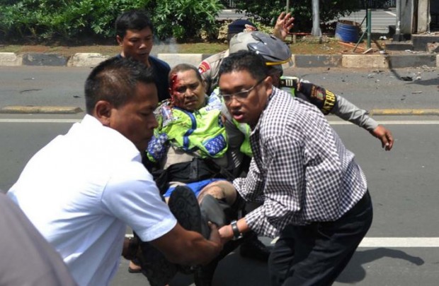 People carry an injured police officer near the site where an explosion went off in Jakarta - AP