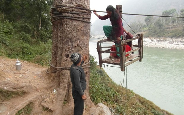 A girl being helped by a local after she crossed Trishuli River using a rope-bridge  Photo: Manish Duwadi / Barcroft India