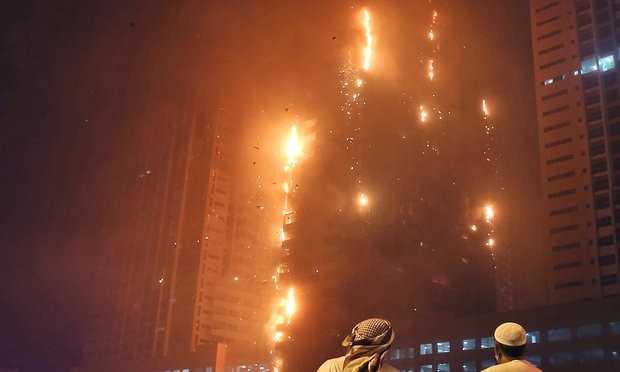 Two Emirati officials watch as a fire spreads up the side of the building in Ajman, United Arab Emirates. Photograph: Kamran Jebreili/AP