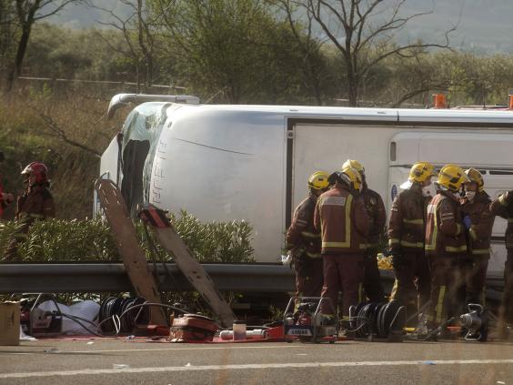 Emergency services personnel stand at the scene of a bus accident (AP)