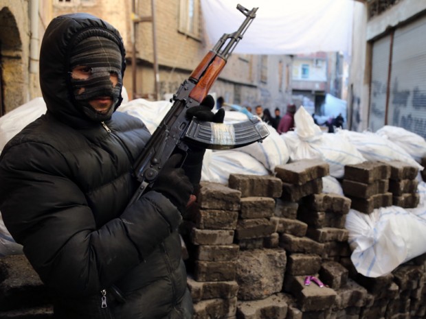 A PKK militant stands at a barricade as some of thousands of people flee from the historic Sur district of the mainly-Kurdish city of Diyarbakir, Turkey.(AP Photo/Murat Bay)