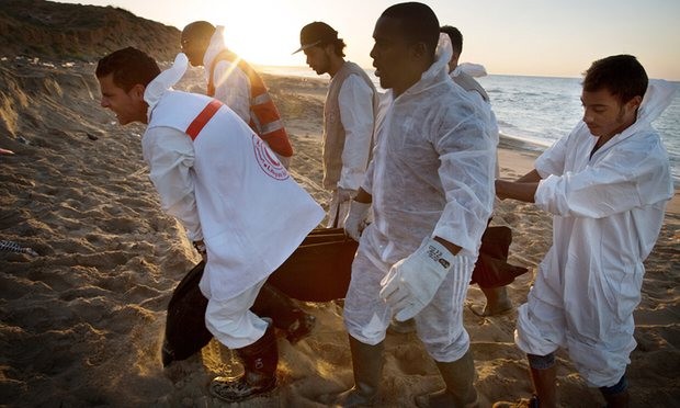 Libyan Red Crescent workers recover a lifeless body of a drowned migrant on the beach in the eastern city of Tripoli, Libya. Photograph: Mohame Ben Khalifa/AP