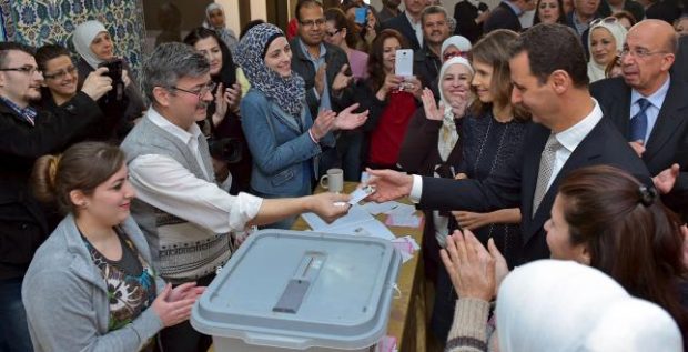 Syria's President Bashar al-Assad his receives his identification card next to his wife Asma (to his right), after casting their votes, inside a polling station during parliamentary elections in Damascus, Syria in this handout picture provided by SANA on April 13, 2016. REUTERS/SANA/Handout via Reuters