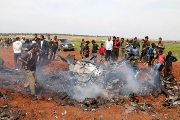 Rebel fighters and civilians gather around the wreckage of a Syrian warplane that was shot down in the Talat al-Iss area, south of Aleppo, Syria April 5, 2016. REUTERS/AMMAR ABDULLAH