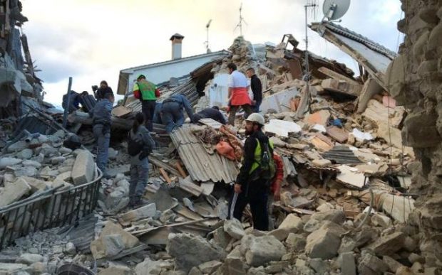 Rescuers at work at  a collapsed house following the quake in Amatrice